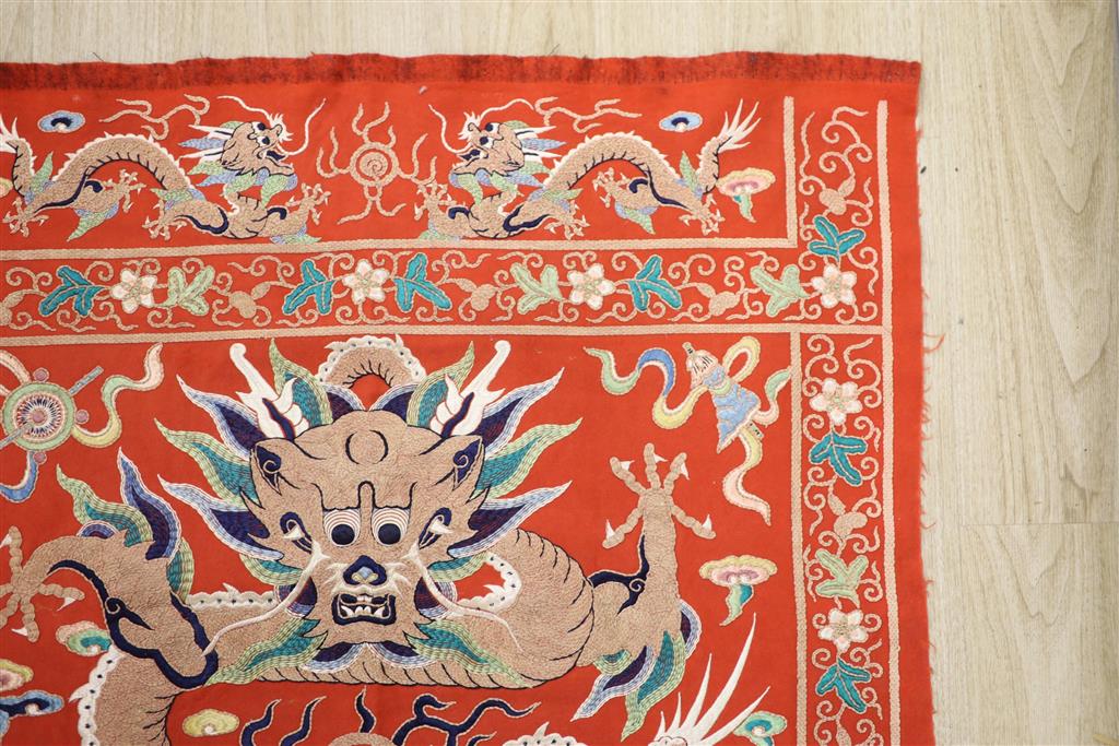 A early 20th century Chinese red felt square panel embroidered with a central motif of a dragon, width 86cm height 84cm